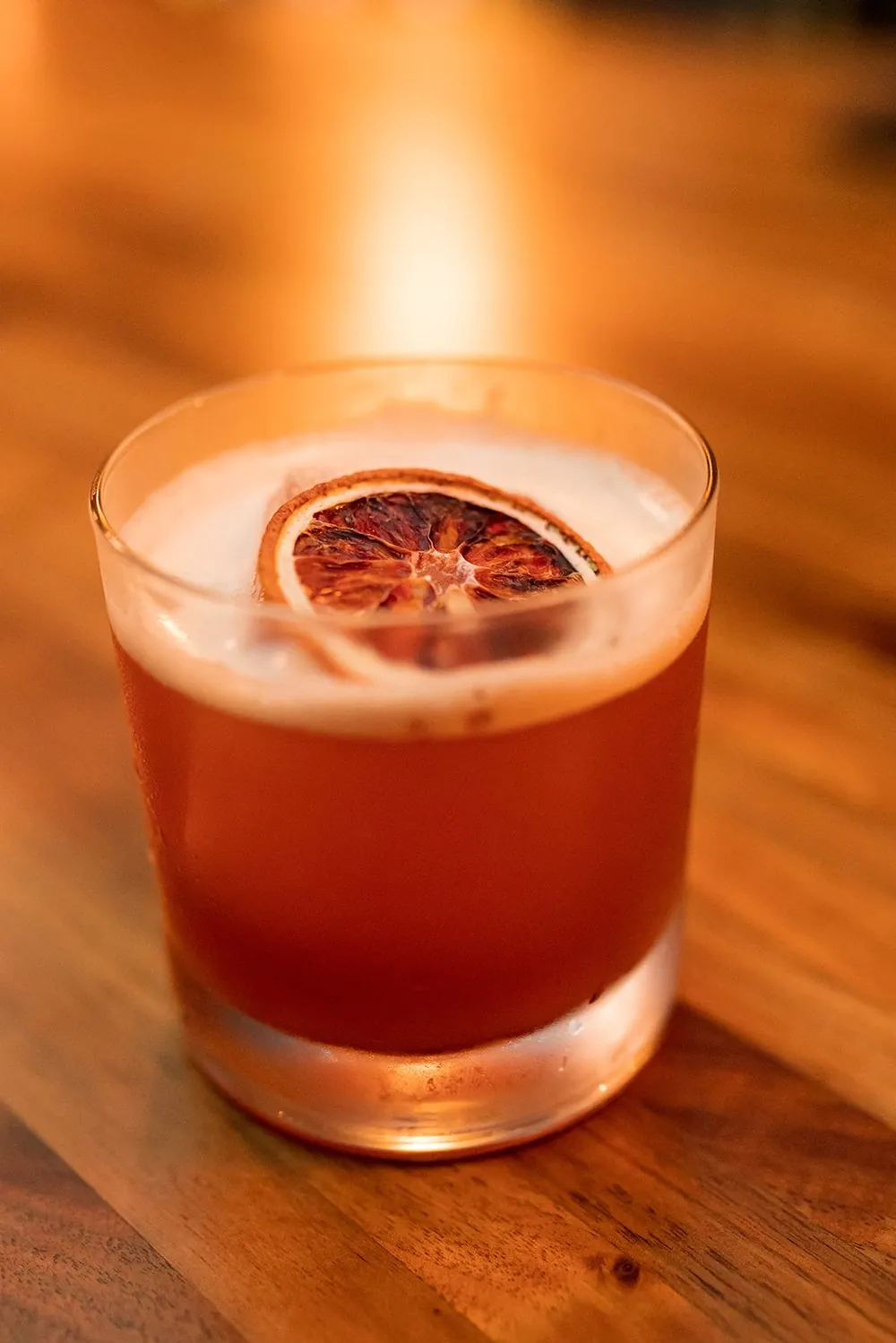 An amber cocktail finished with a dried citrus wheel