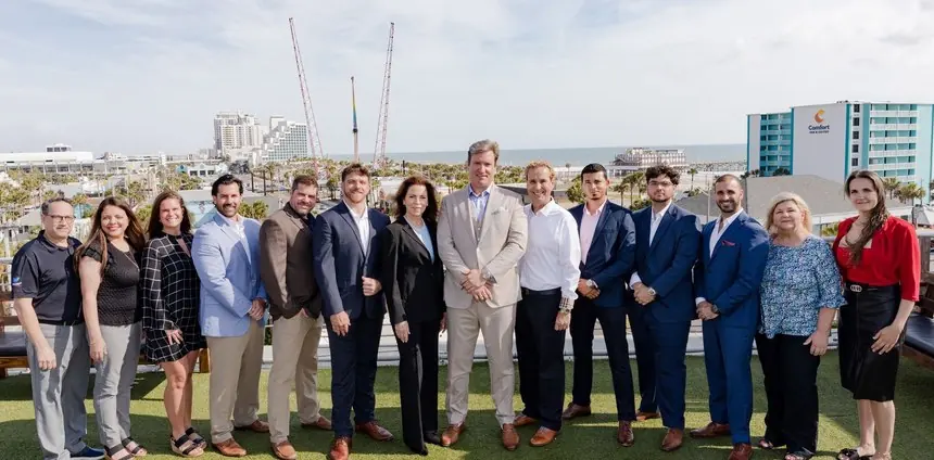 A company team photographed on a rooftop overlooking the beach