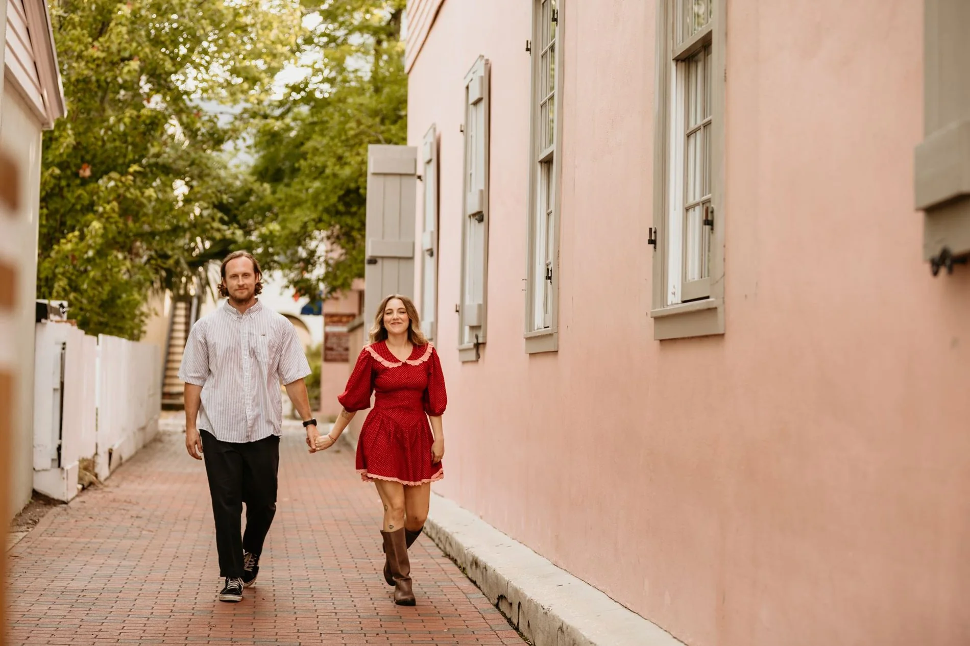 Maggie and Aaron walking a pink old-town alley in St. Augustine, Florida