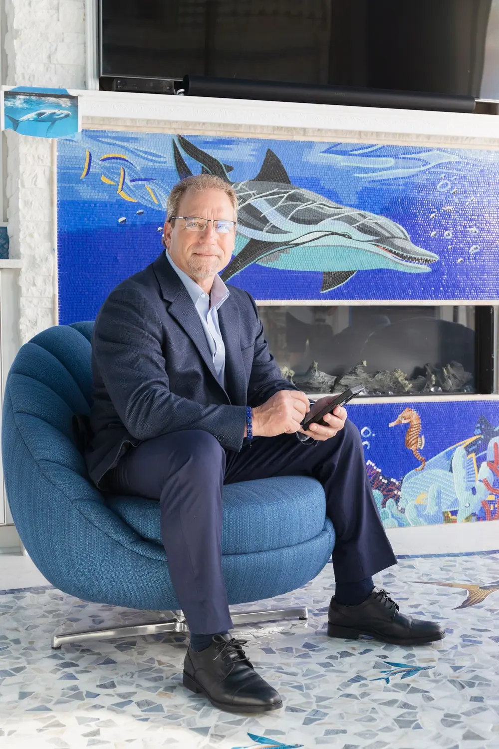 Frank Russo photographed beside the dolphin mosaic fireplace inside his castle home