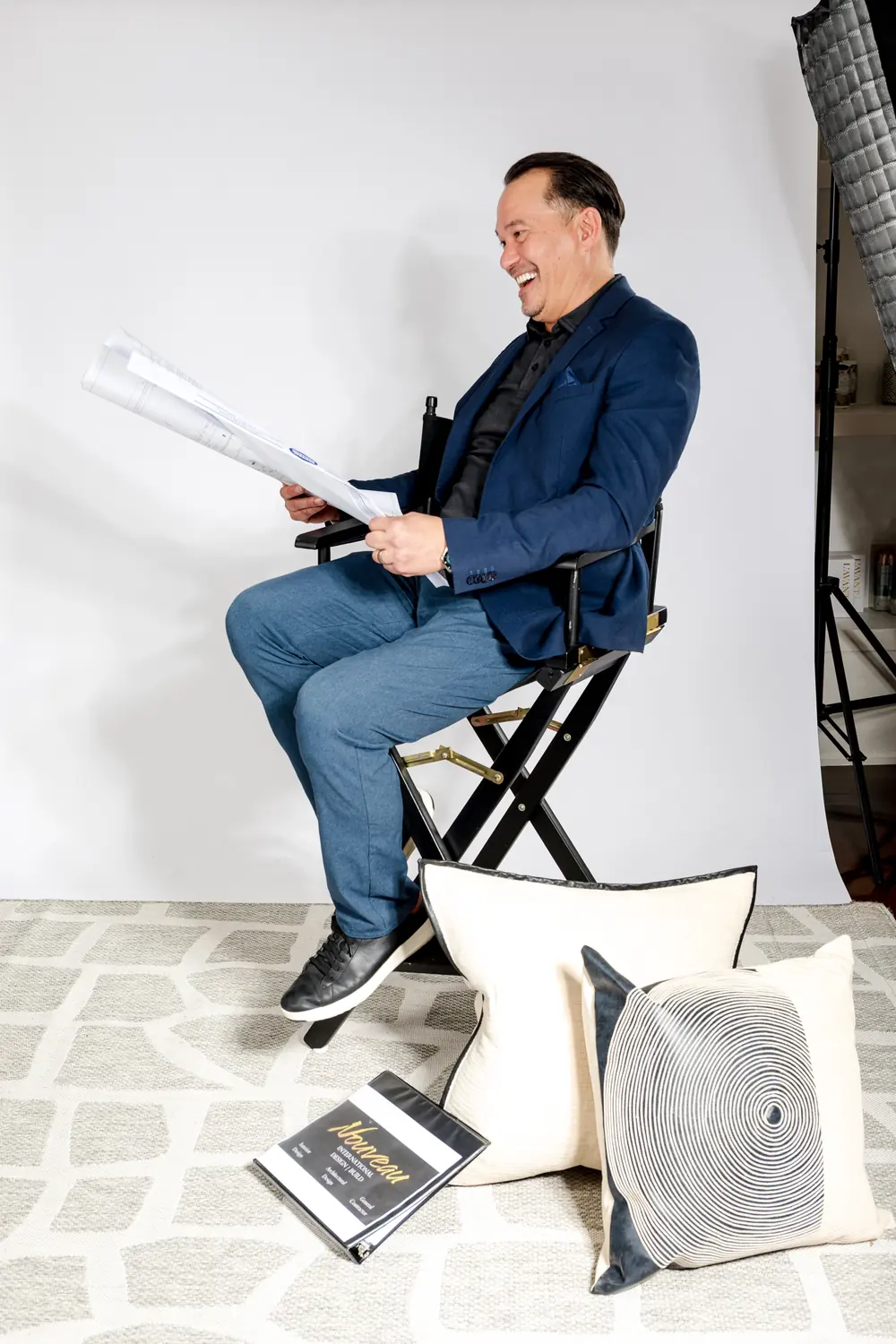 The founder of Nouveau Design Build photographed on set with his plans