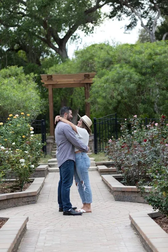 Rachel and Josh embracing in a rose garden at their engagement session
