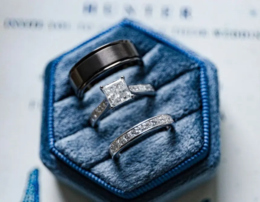 Wedding rings in a velvet box on the couple's beach invitation