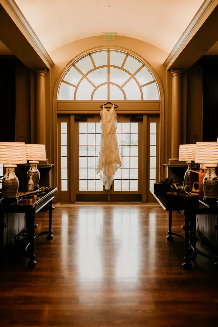 The beaded wedding gown hanging in an arched window