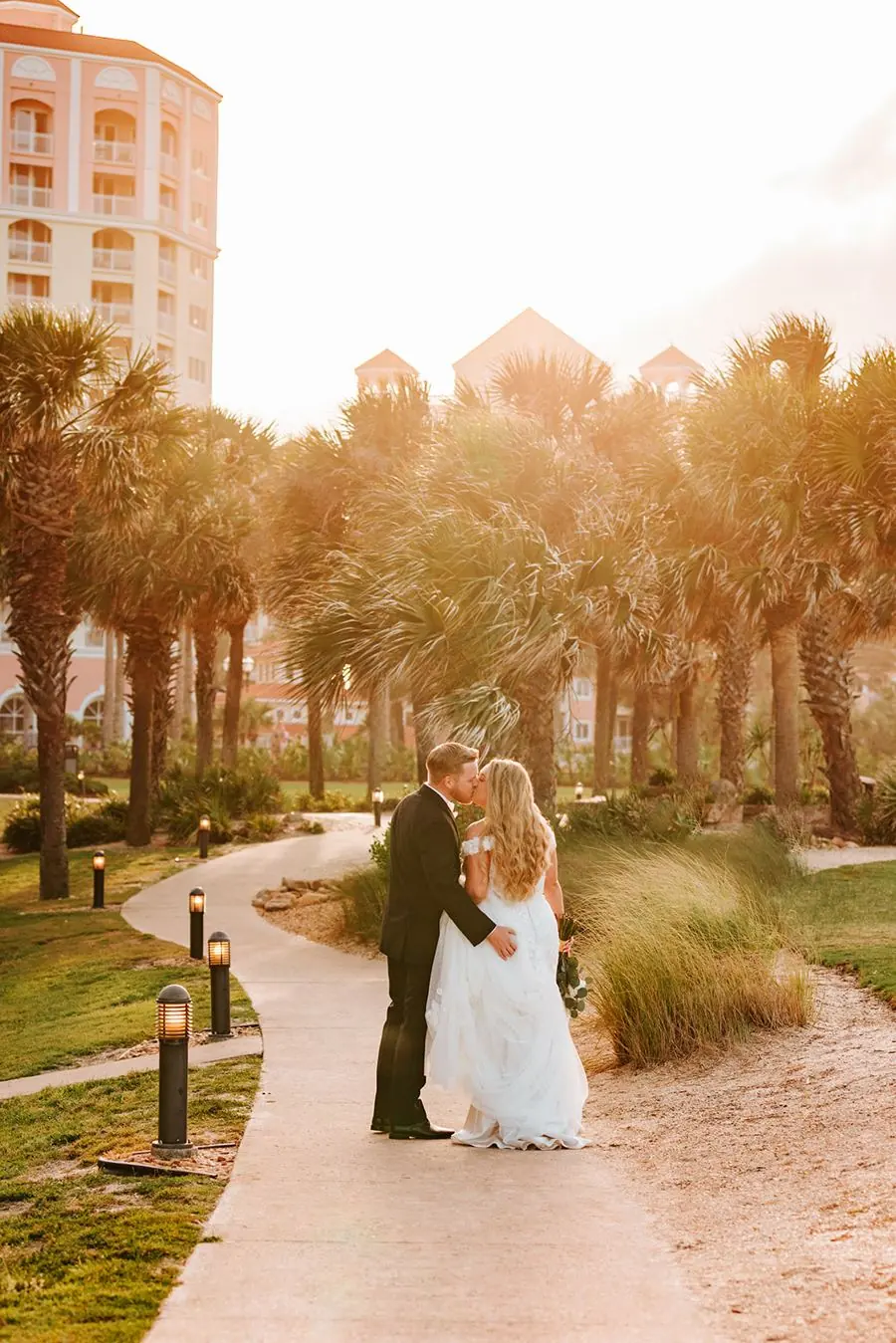 Hammock Beach Resort wedding kiss with the resort towers at golden hour