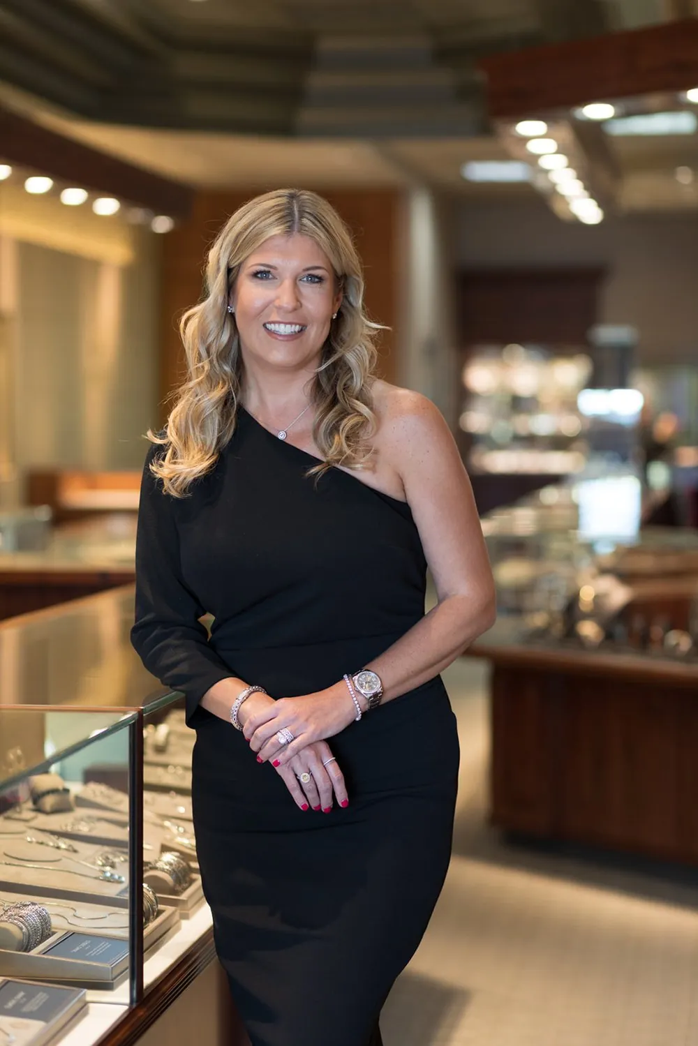 A jeweler leaning on the display case in her showroom