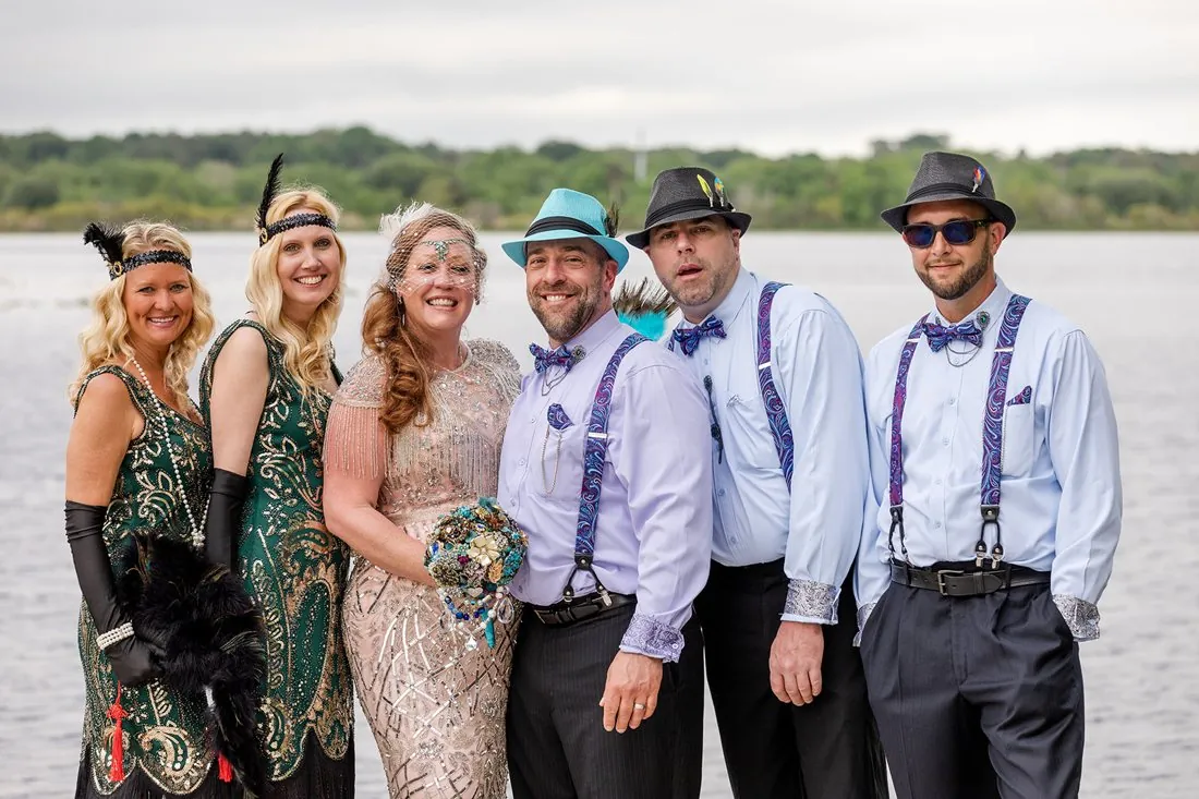 The full 1920s wedding party posing by the lake