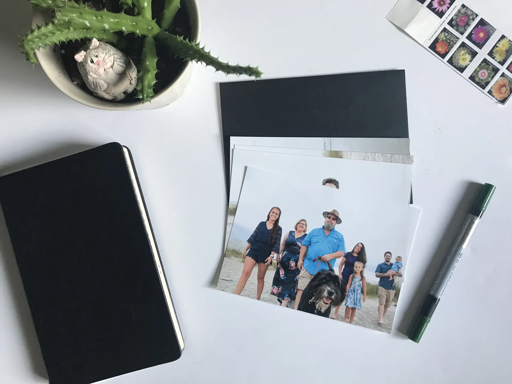 Printed family photographs arranged in a flat-lay with a journal and keepsakes