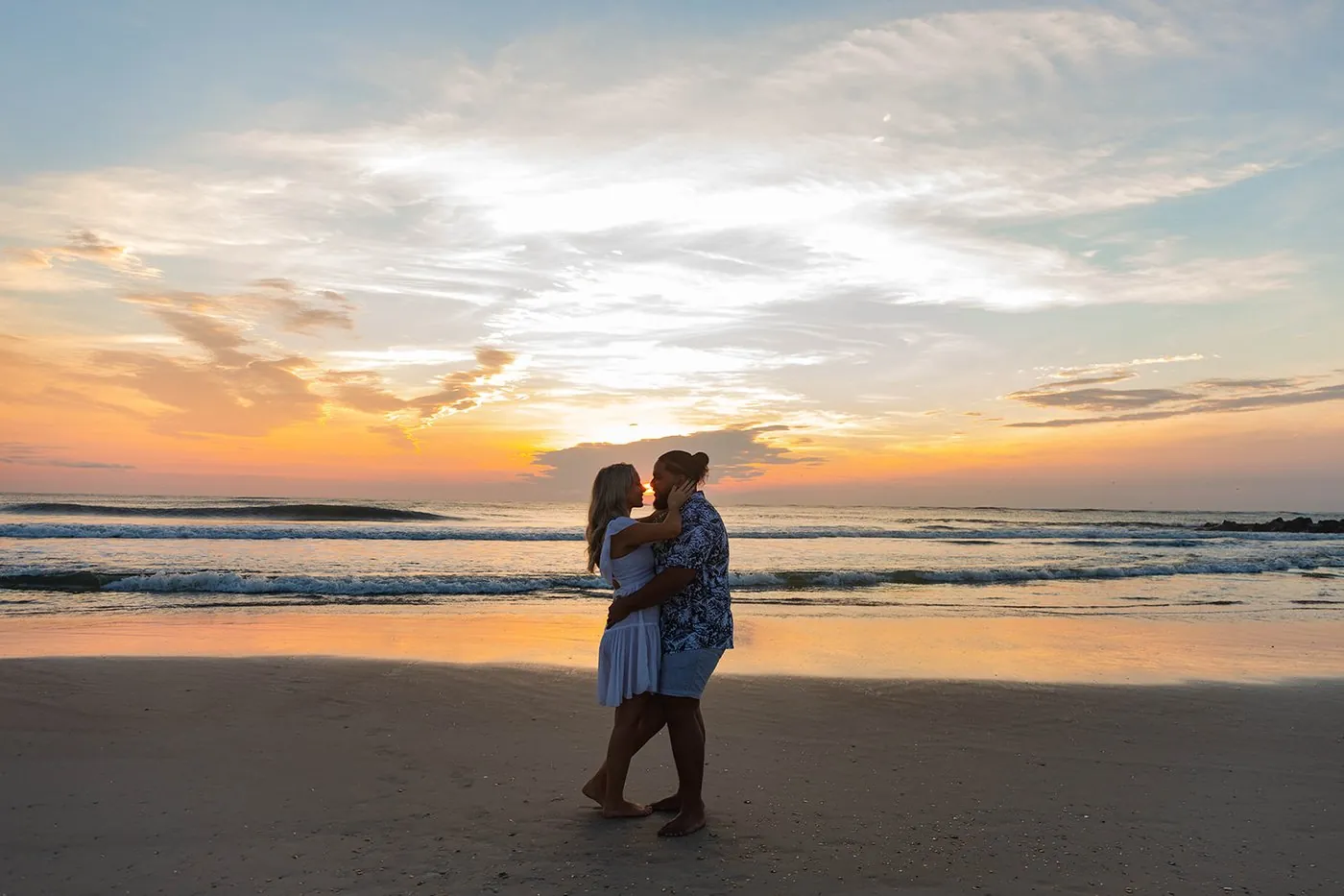 A couple embracing in silhouette against the sunset on the beach