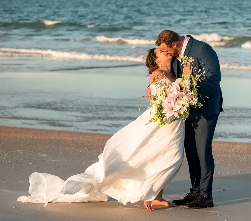Bride and groom kissing at sunset on the beach