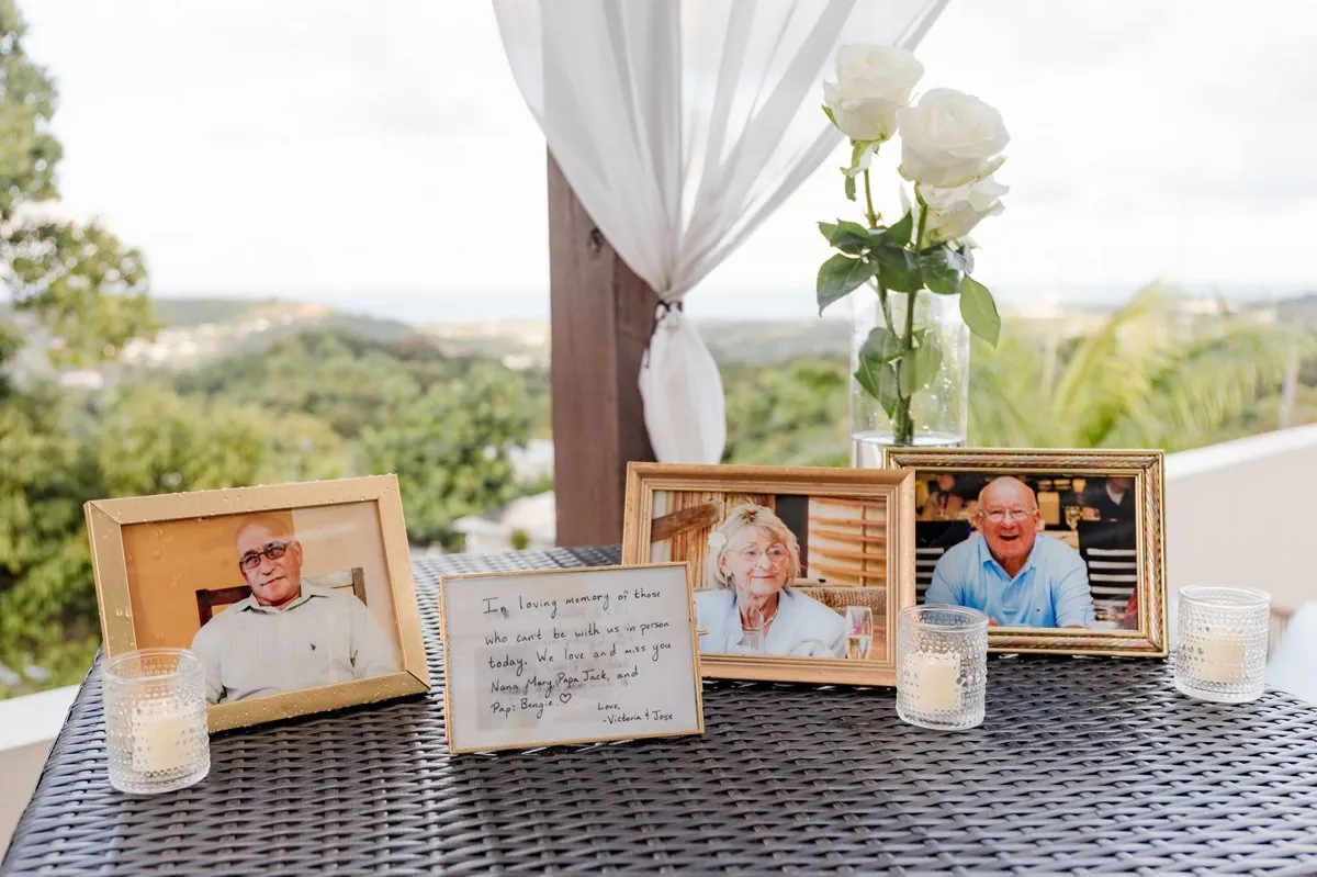 A memorial table with framed photos, roses and candles overlooking the rainforest