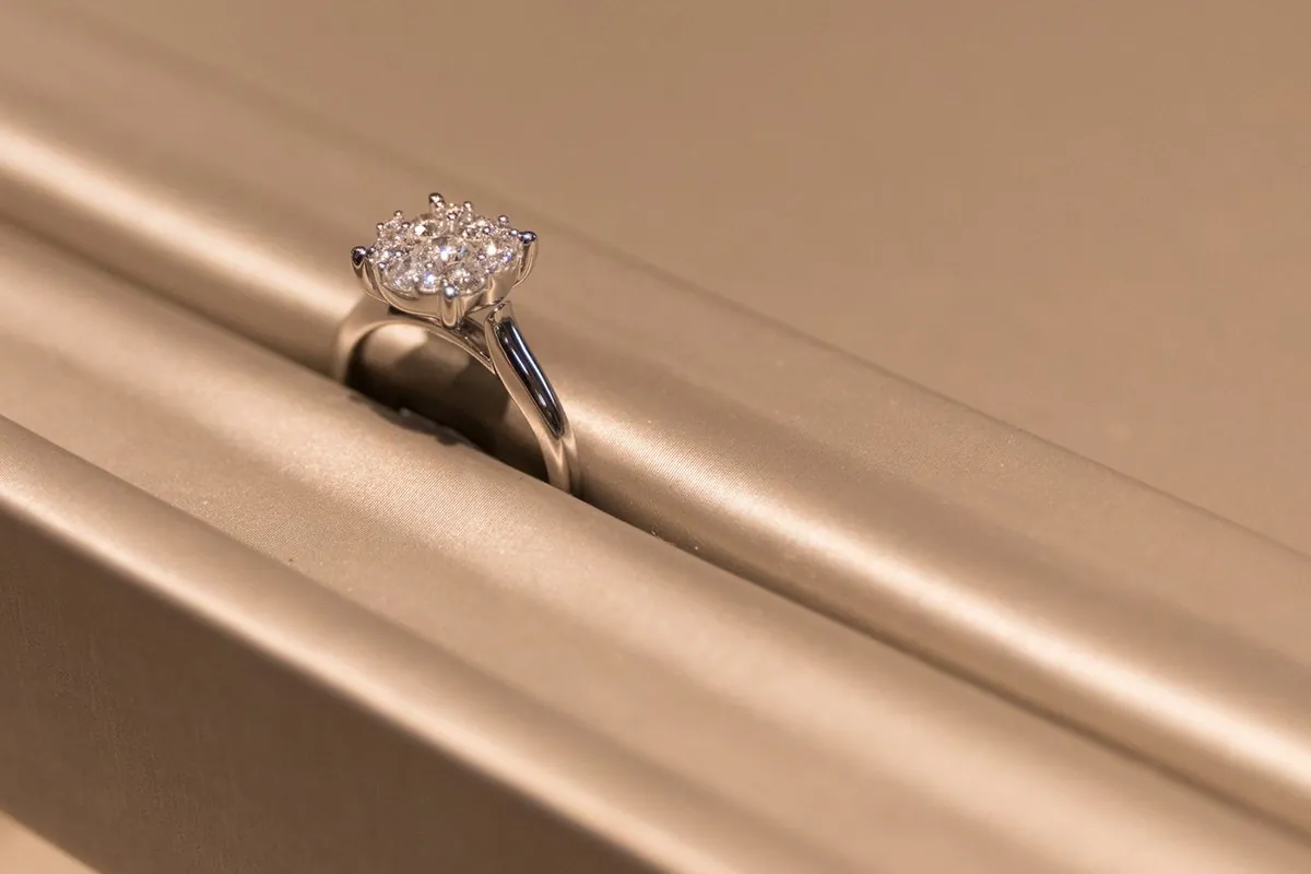 A diamond cluster ring photographed on champagne satin