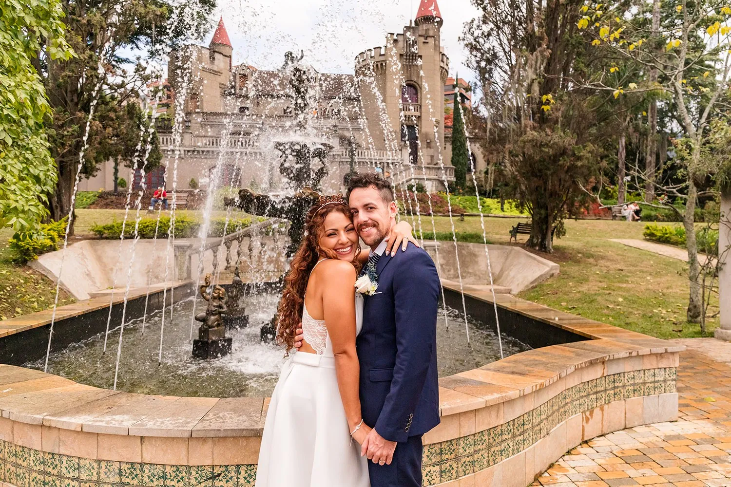 Nataly and Joey embracing in front of the castle fountain at El Castillo, Medellin