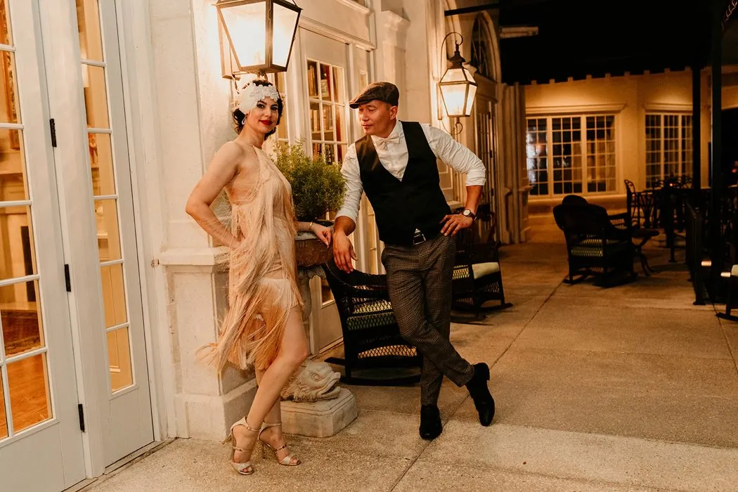 The bride in a fringe flapper dress and the groom posing under the lanterns