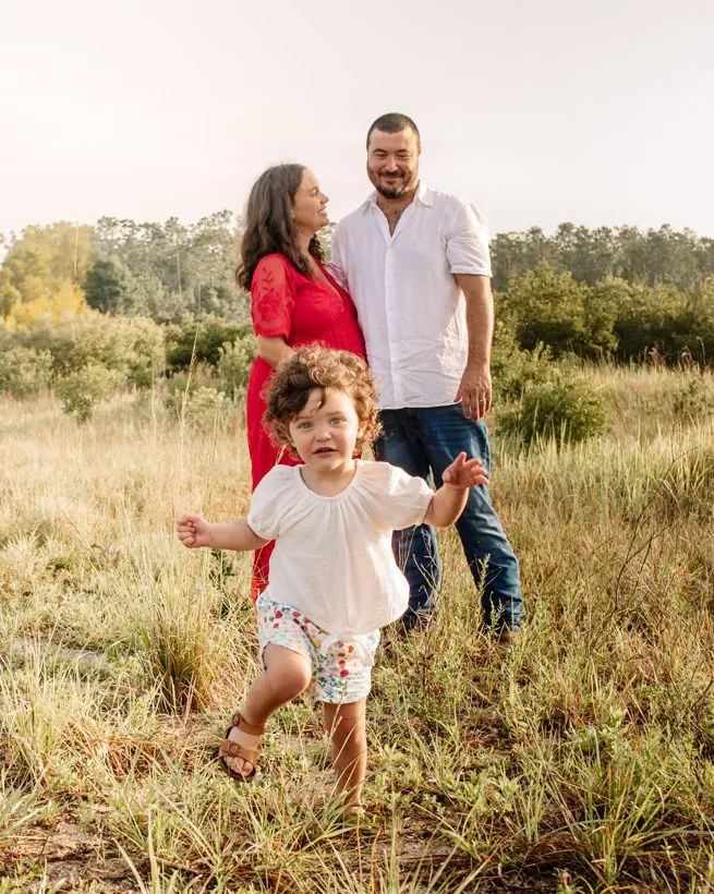 Rachel and Josh with their little girl running through a field