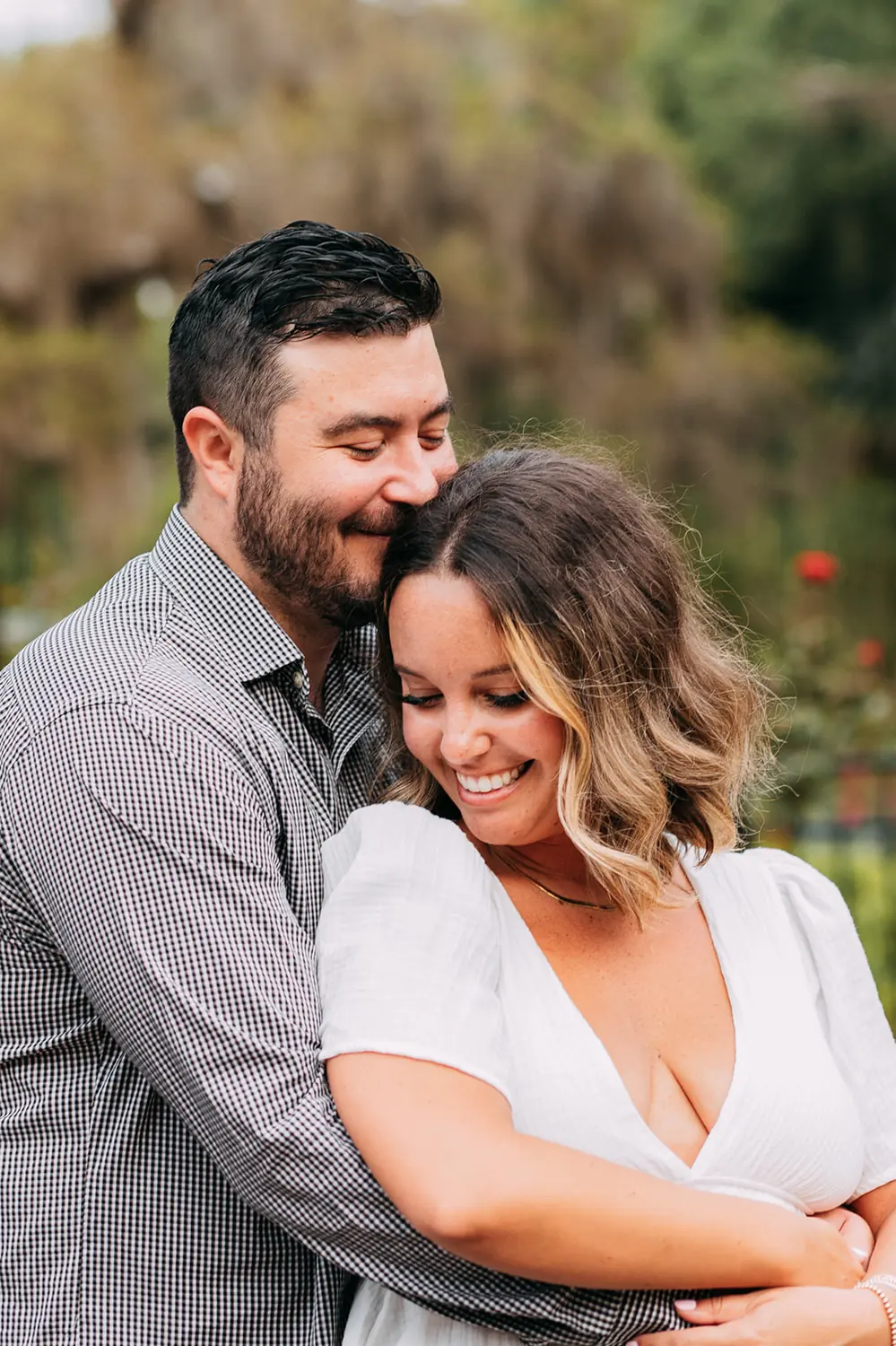 Rachel and Josh embracing in a rose garden during their engagement session