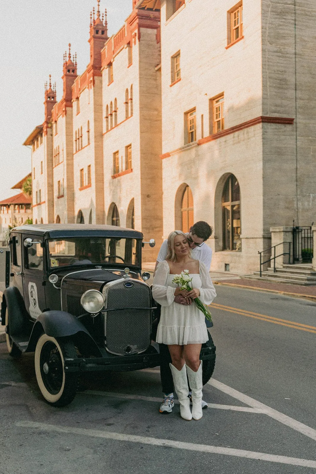Couple by a vintage car in front of Flagler College at sunset, St. Augustine