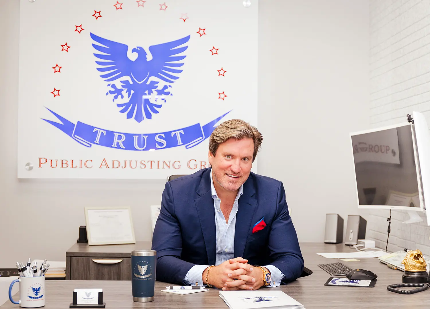 The founder of Trust Public Adjusting Group at his desk beneath the company crest