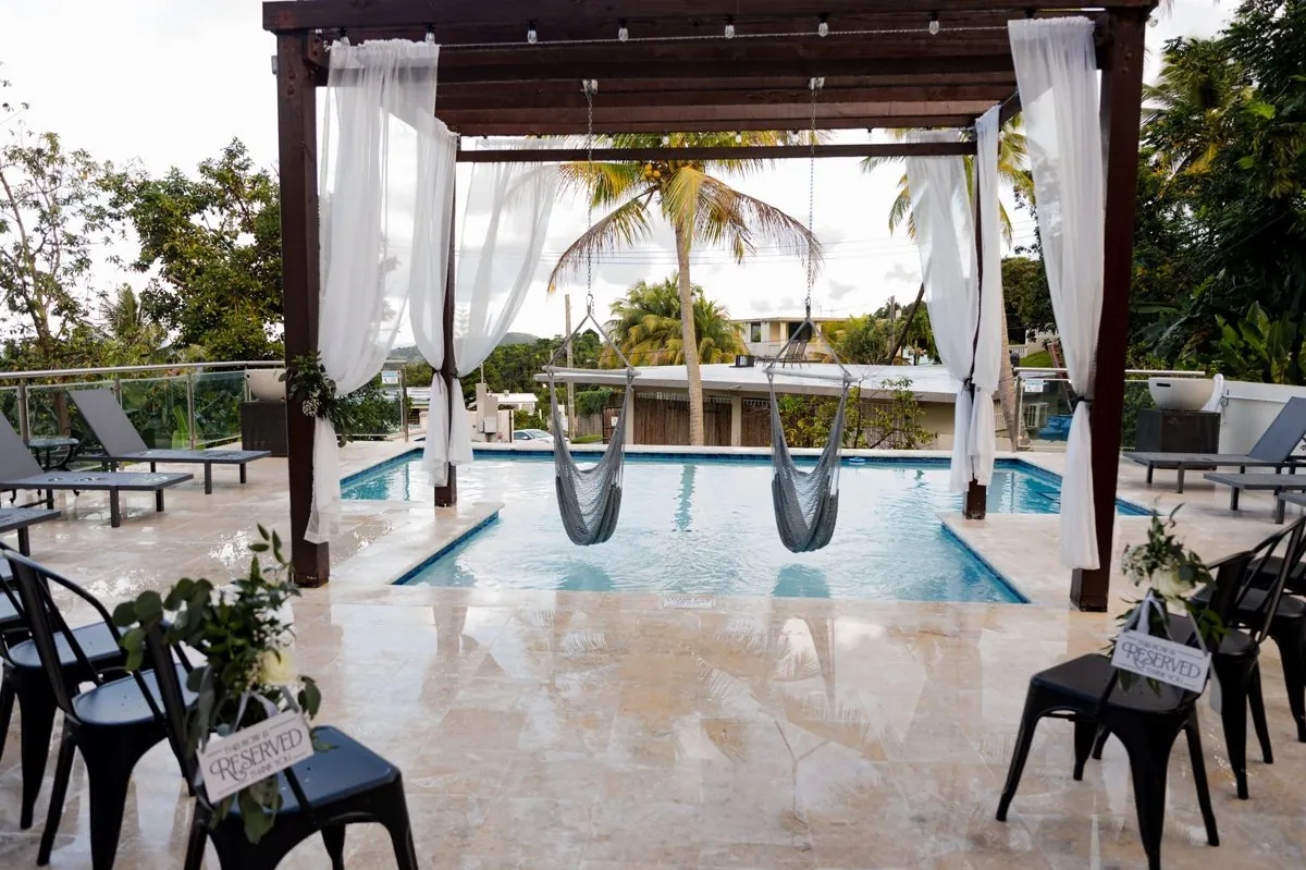 The poolside ceremony setup with a draped pergola and palm trees at Casa Bella, Puerto Rico