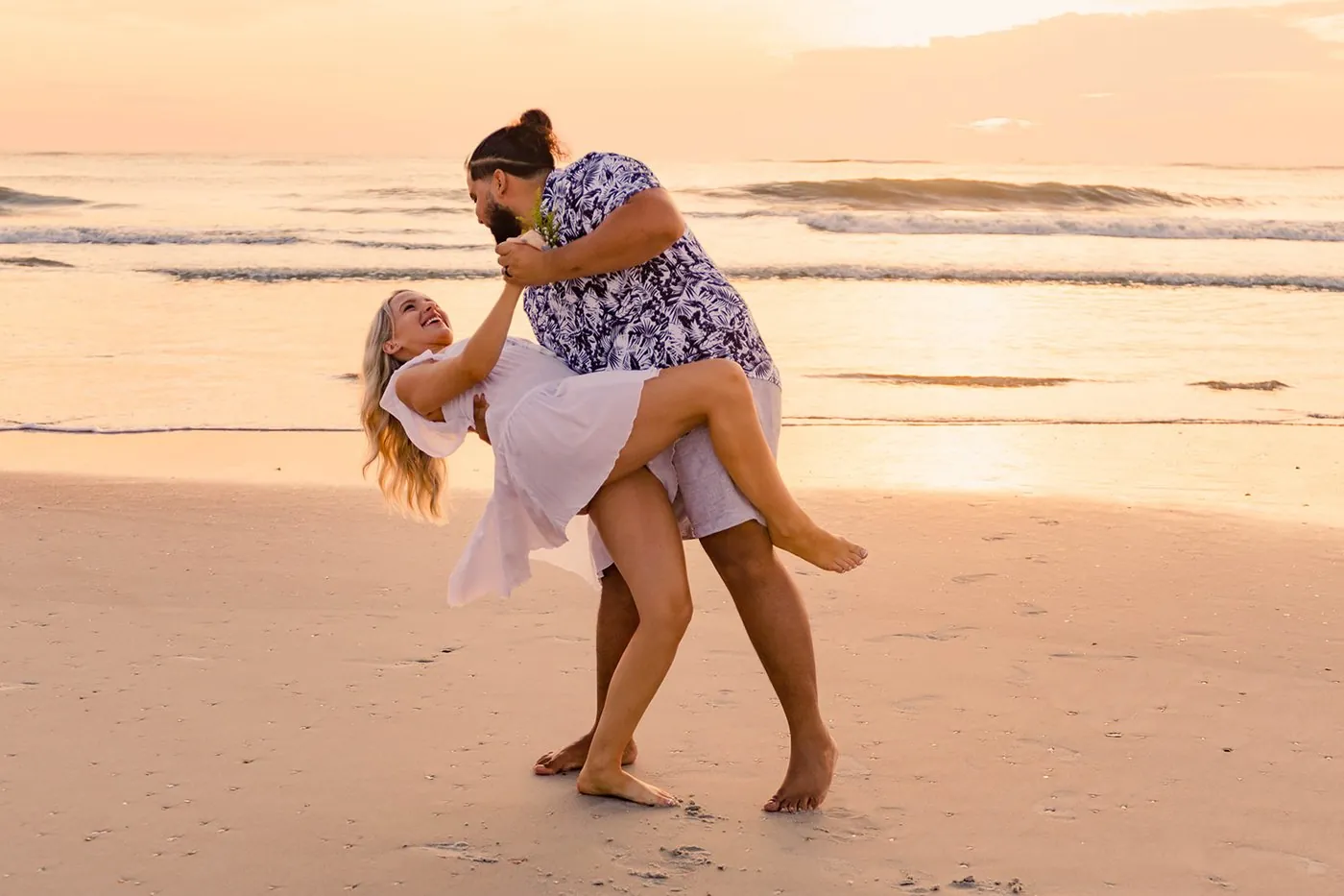 A couple dancing and dipping on the beach at sunset during their elopement