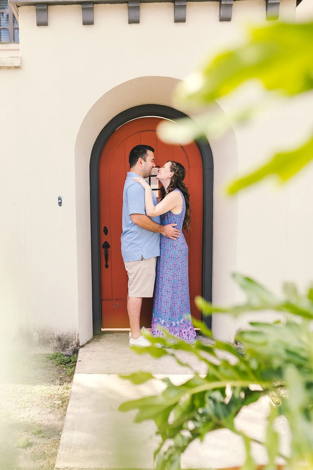 Katie and Daniel about to kiss in a red arched doorway in historic St. Augustine