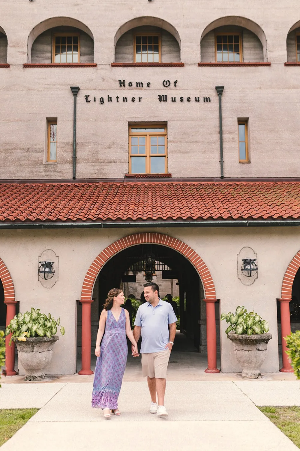 Katie and Daniel walking hand in hand in front of the Lightner Museum in St. Augustine