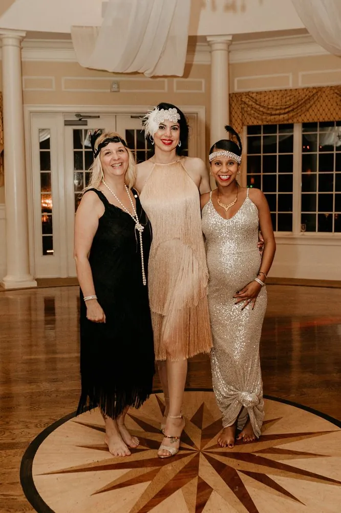 Three guests in flapper dresses posing on the compass-rose ballroom floor
