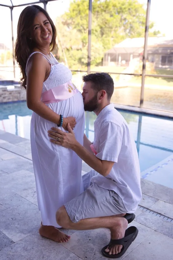 Paola pregnant with Lily, Leighton kneeling to kiss the belly
