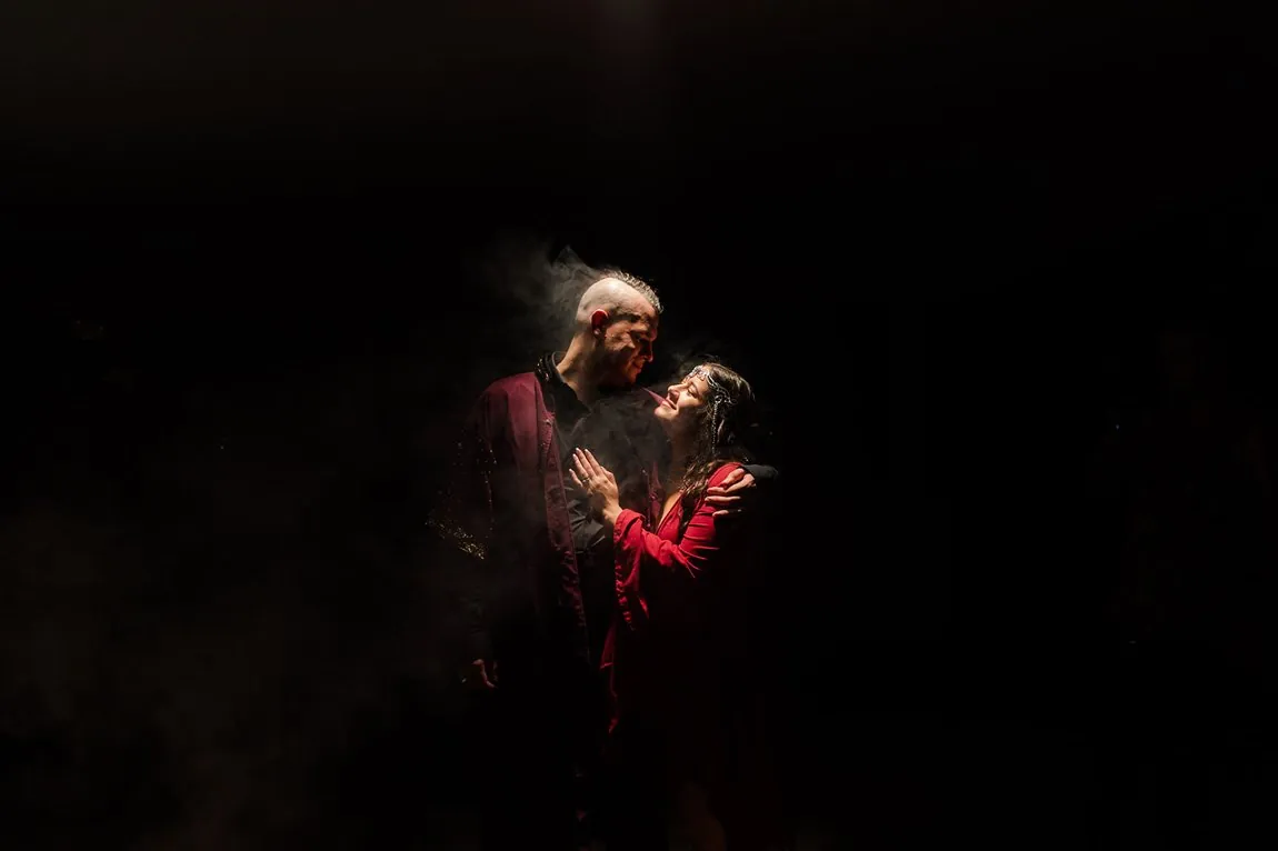A Lord of the Rings themed couple lit by red light and smoke, the bride in a mithril crown