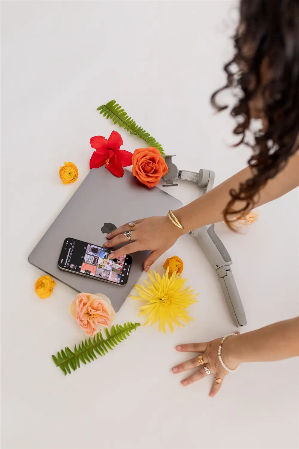 An editorial flat-lay for a content creator, styled with flowers and a gimbal