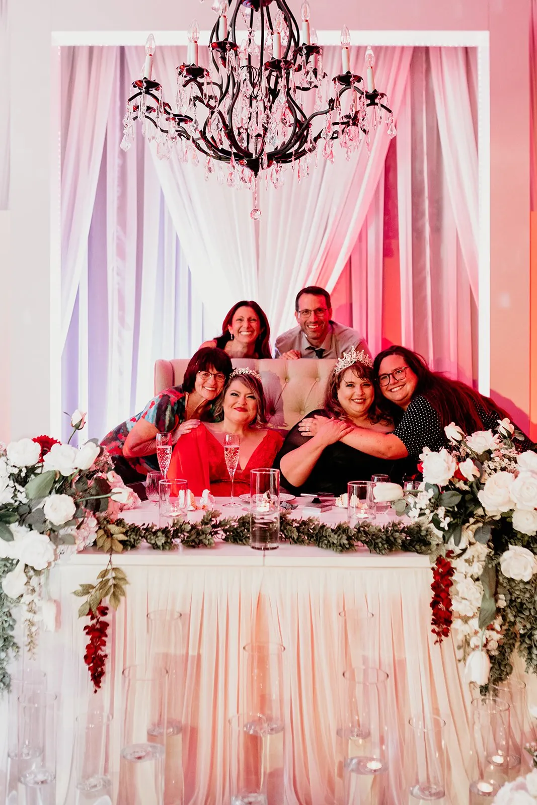 The two brides surrounded by their family at the sweetheart table
