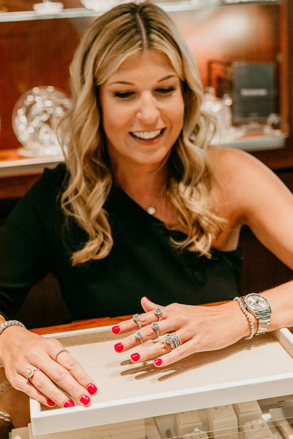 A client trying on rings at the counter, delighted
