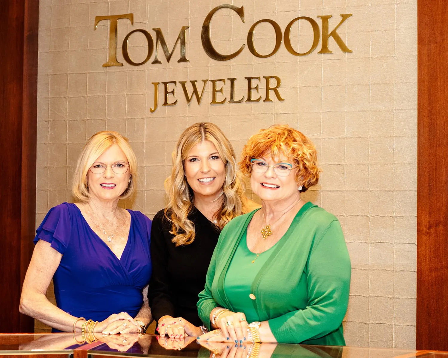 The team of Tom Cook Jeweler photographed under their gold storefront sign