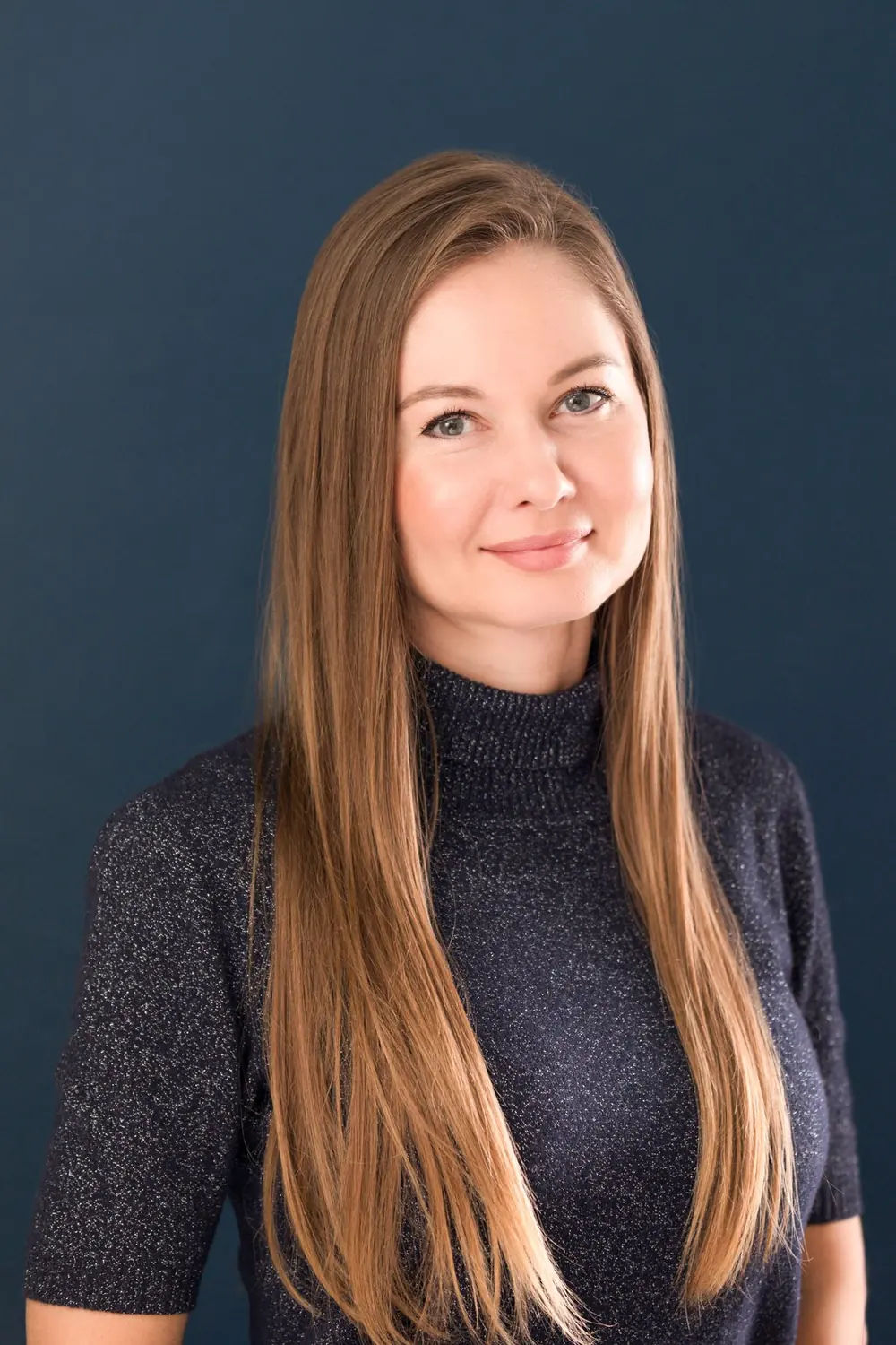 Studio headshot of a professional woman on a navy backdrop