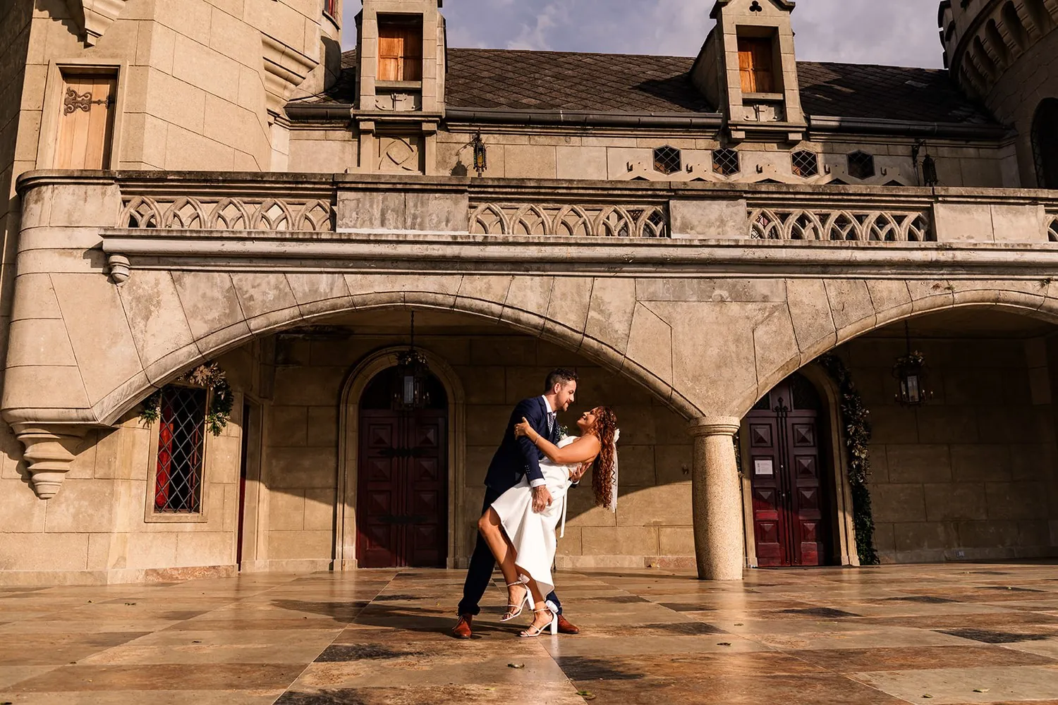 Joey dipping Nataly for a kiss under the stone arch of the castle courtyard in Medellin