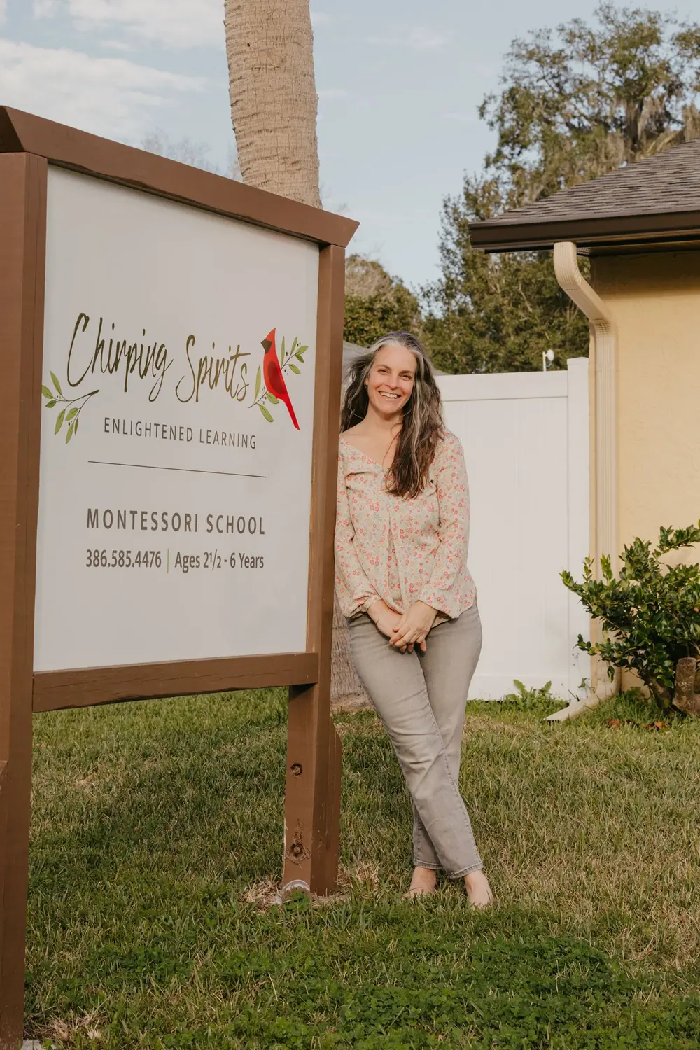 The founder of Chirping Spirits Montessori School beside her school sign