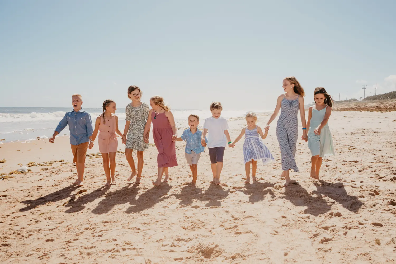 A long line of children walking hand in hand down a Flagler Beach shoreline